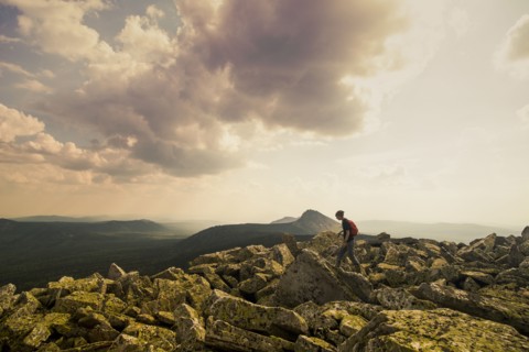 Caucasian hiker walking in rocky field in remote landscape