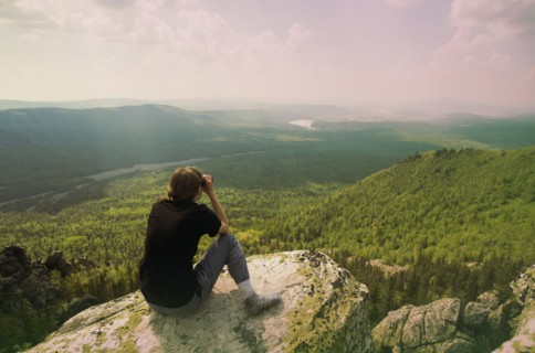 Caucasian hiker admiring remote landscape from rocky hilltop