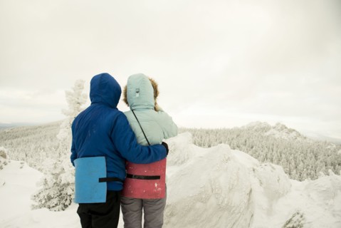 Caucasian hikers on mountaintop admiring snowy landscape