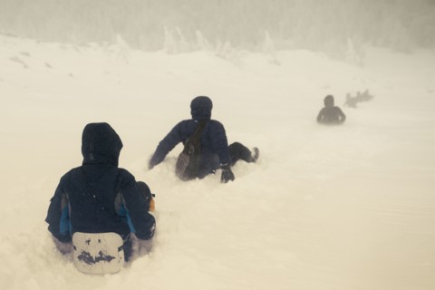 Caucasian hikers sledding on snowy hill