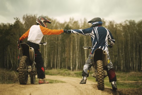 Caucasian men bumping fists on dirt bikes