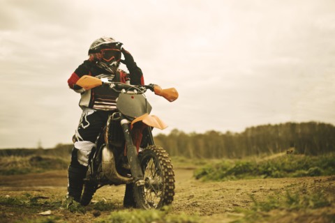 Caucasian man riding dirt bike in field