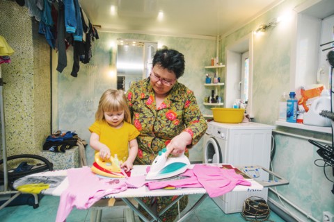 Caucasian grandmother and granddaughter ironing laundry