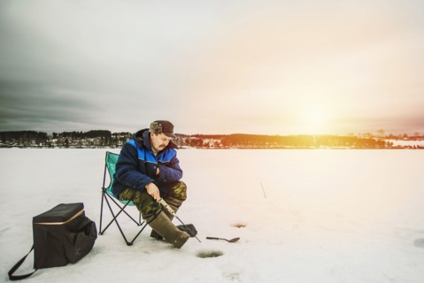Man ice fishing in frozen lake