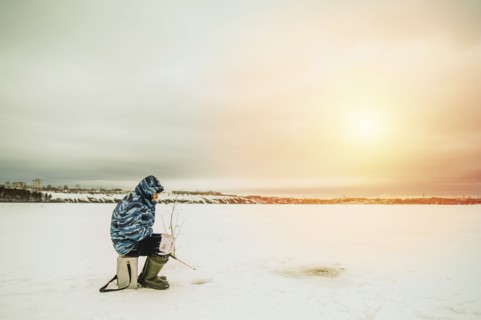 Man ice fishing in frozen lake