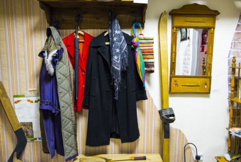 Coats on coathanger near skis and hockey stick
