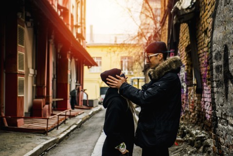 Man holding head of woman in urban alley