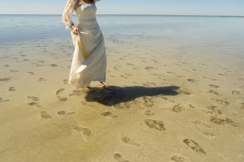 Footprints of bride wading in ocean at beach