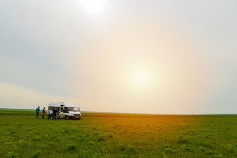 Caucasian friends standing in field near van