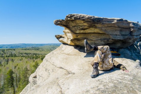 Caucasian man laying on mountain rock under blue sky