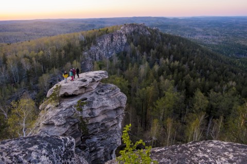 Caucasian friends standing on mountain rock admiring scenic view