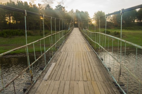 Sunbeams on wooden footbridge over river