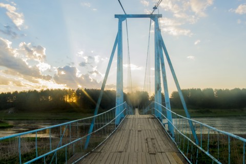 Sunbeams on wooden footbridge over river