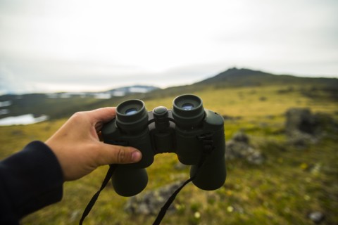 Hand of man holding binoculars outdoors
