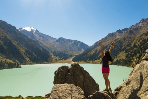 Caucasian woman celebrating on rocks near mountain lake
