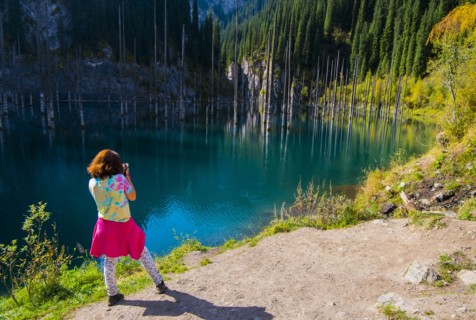 Caucasian woman photographing trees in lake