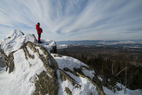Caucasian man standing in snow admiring scenic view of forest
