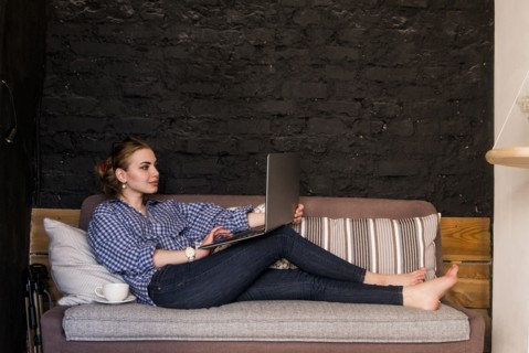 Caucasian woman sitting on sofa using laptop