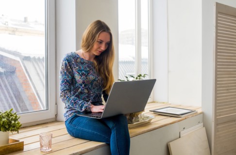 Caucasian woman sitting at window using laptop