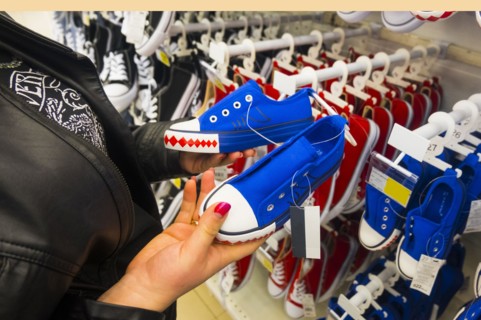 Hands of Caucasian woman holding sneakers in store