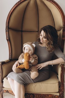 Caucasian mother sitting in armchair with baby son wearing bear costume