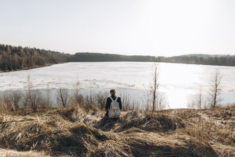 Middle Eastern woman sitting in grass near lake