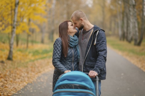 Affectionate Middle Eastern couple with stroller in park