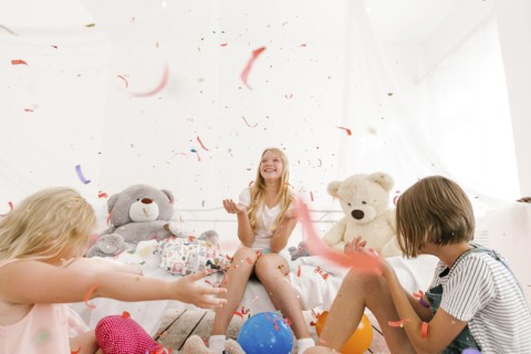 Middle Eastern sisters throwing confetti in bedroom