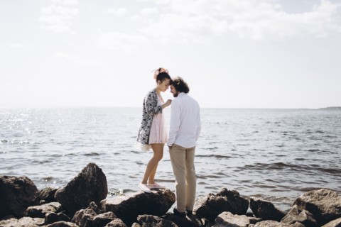 Middle Eastern couple standing on rocks near ocean