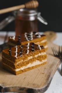 Slices of layer cake on cutting board with honey