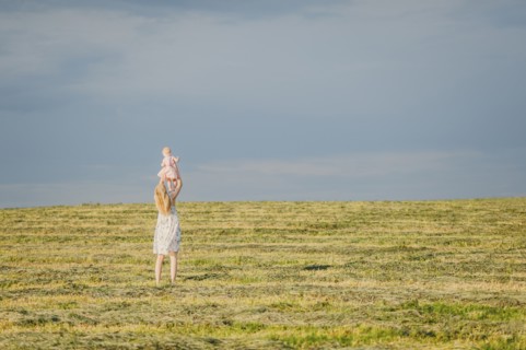 Mother lifting baby daughter in field