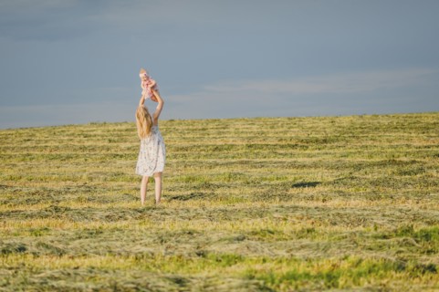 Mother lifting baby daughter in field
