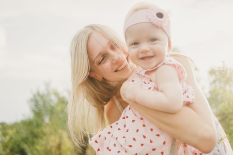 Mother hugging baby daughter on sunny day
