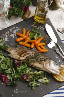 Grilled fish and salad on stone plate