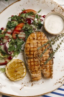 Grilled fish and salad on plate with sauce