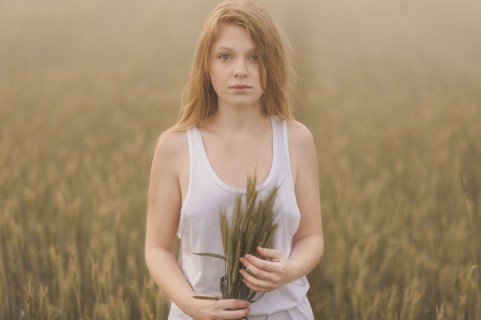 Middle Eastern teenage girl holding wheat in field