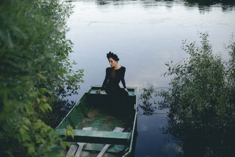 Middle Eastern woman wearing black dress in boat on lake