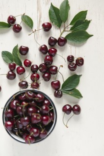 Cherries and bowl on white wooden table