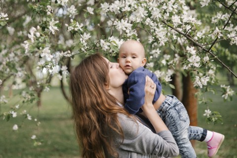 Middle eastern mother kissing son under flowering tree