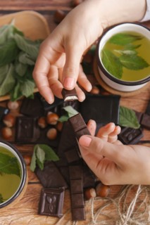 Hands of woman breaking chocolate near green tea