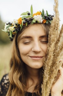Middle Eastern woman wearing flower crown holding wheat to face