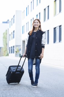 Mixed race woman rolling luggage