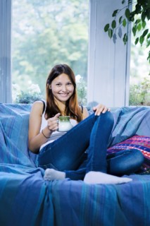 Mixed race woman drinking coffee on sofa
