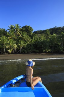Hispanic woman sitting in boat near beach