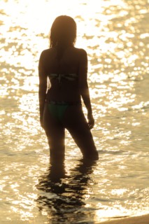 Silhouette of Mixed Race woman wading in ocean at sunset