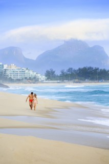 Couple walking on beach near waves