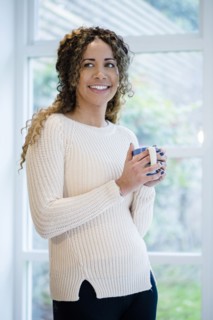 Woman standing near window holding coffee cup