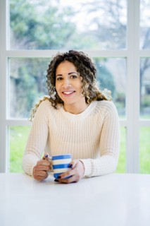 Smiling woman sitting at table holding coffee cup