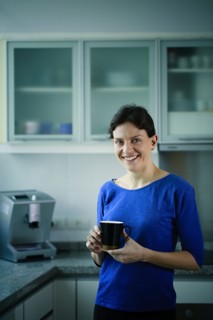 Smiling Caucasian woman drinking coffee in kitchen