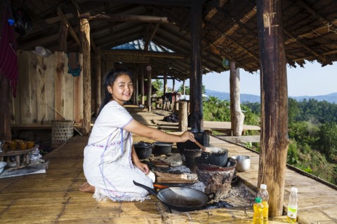 Smiling Asian woman cooking on patio outdoors